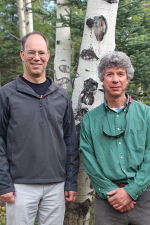 two men posing for a photo in front of aspen trees