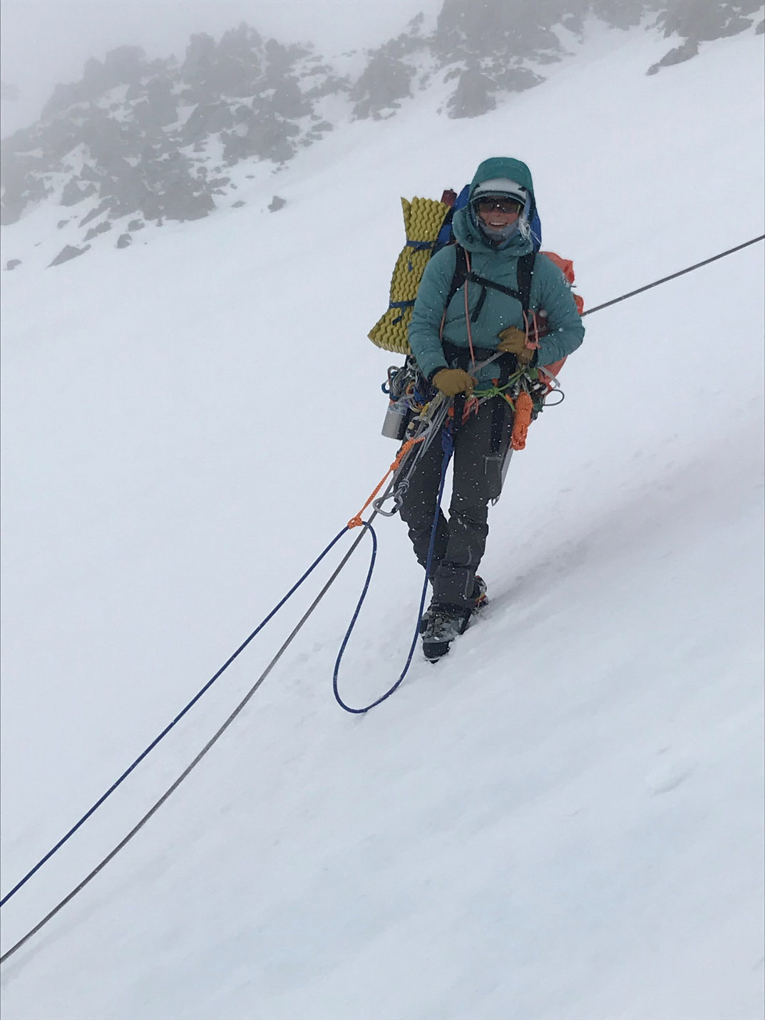 female mountaineer attached to ropes on a steep icy slope