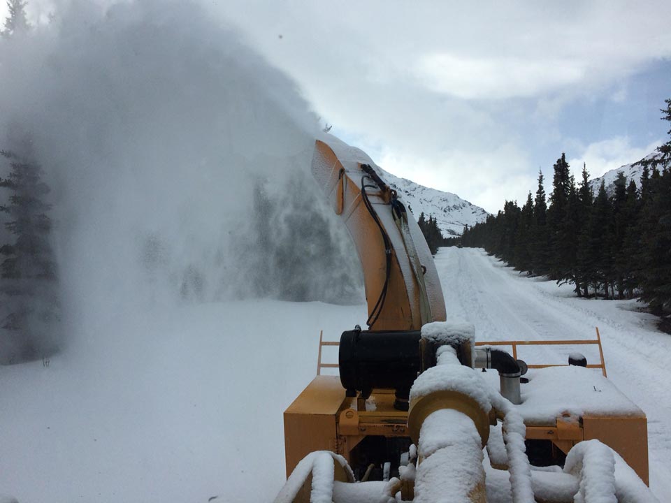 a large piece of equipment blowing snow off a road