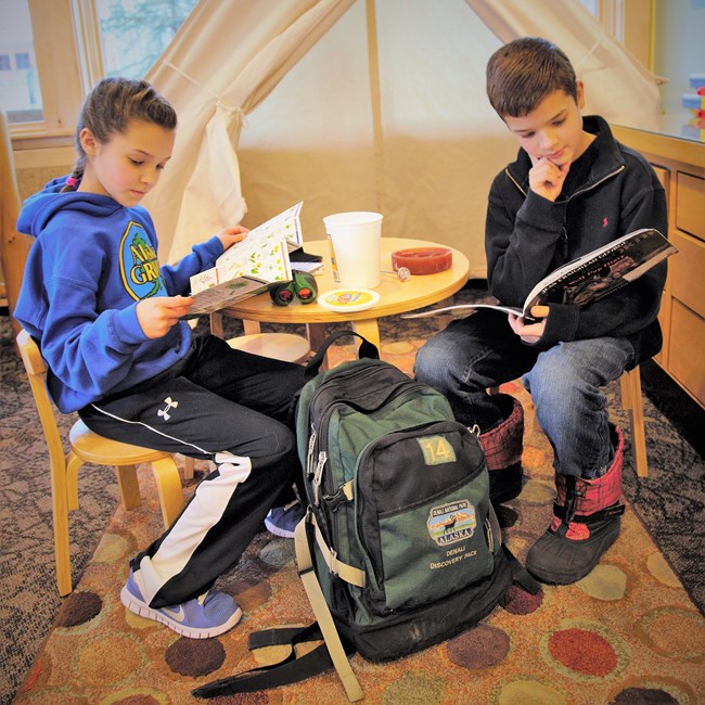 Two young visitors study the contents of a Denali Discovery Pack