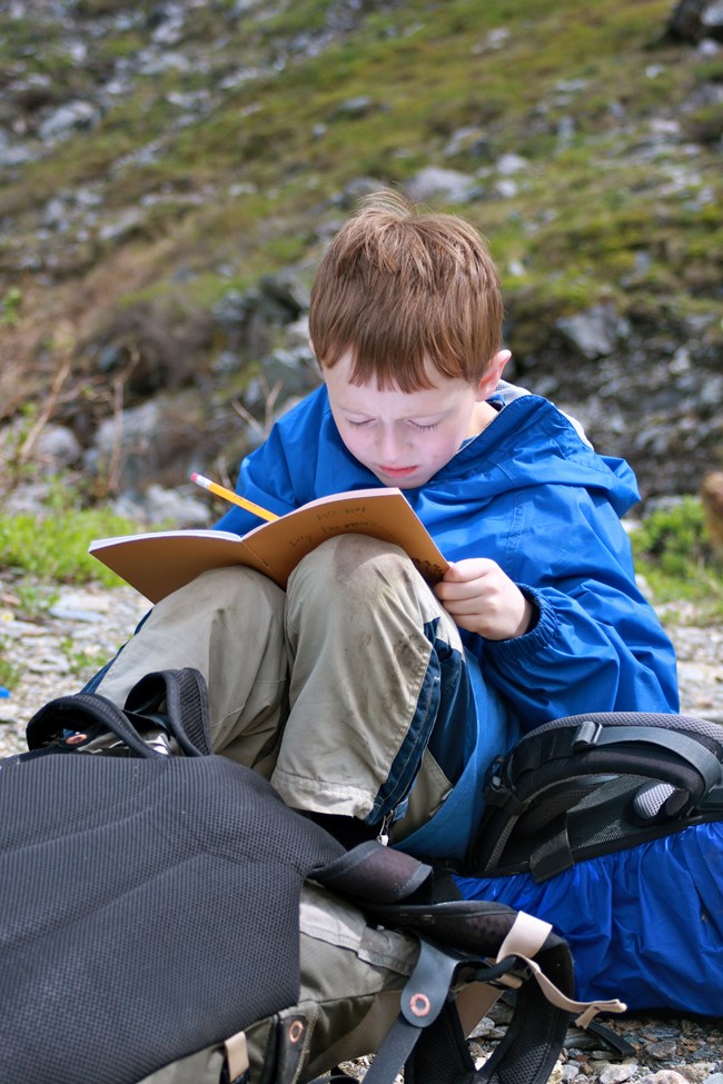 a child sits on the tundra writing in a journal