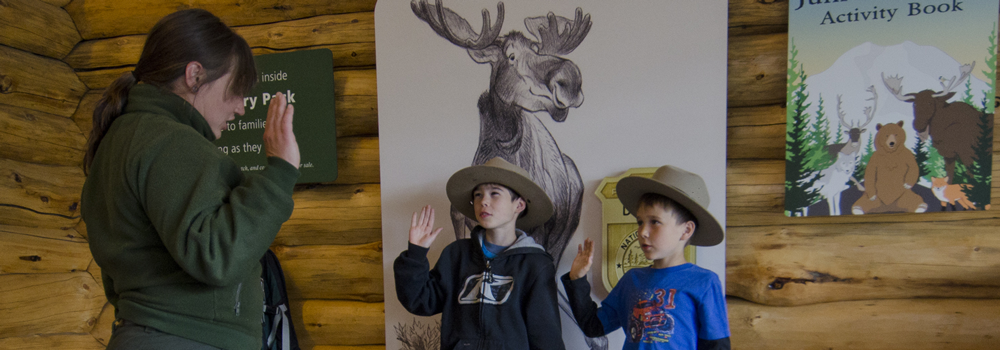two junior rangers are sworn in by a park ranger