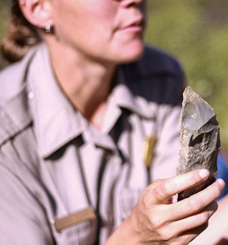 Female ranger holds a stone tool