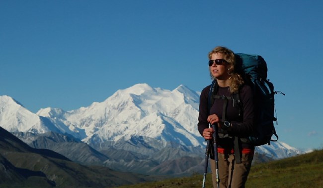 Woman wearing a backpack with vast snowy mountain in background