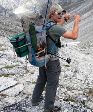 Climber carrying backpack with green CMC canister strapped to it.