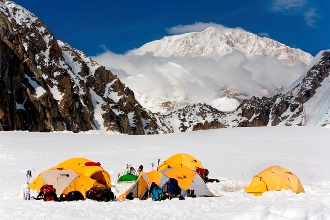 Expedition tents on glacier; snowy mountain in the distance