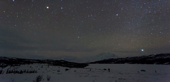 snowy landscape under a night sky filled with stars