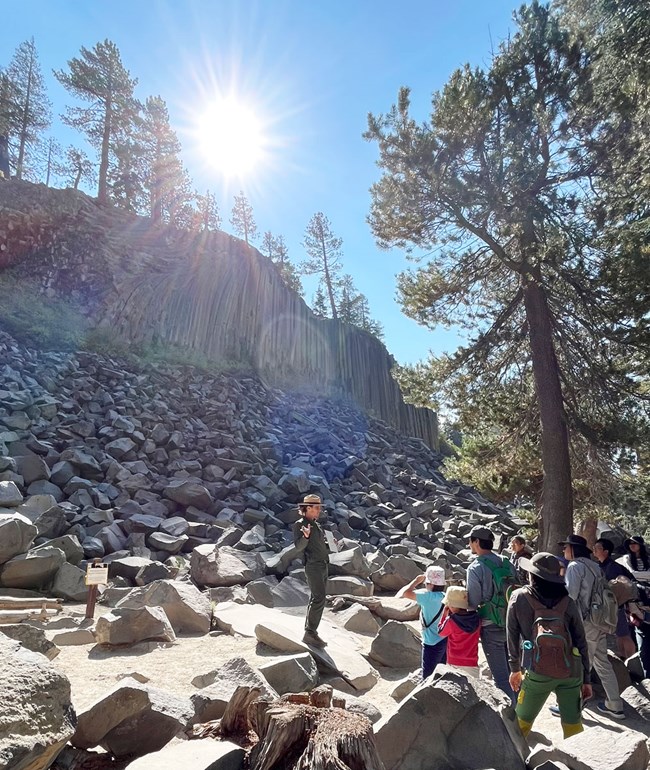 Ranger talking to a group of people with Devils Postpile in the background