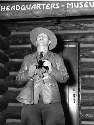 A park ranger looks up holding a pair of binoculars