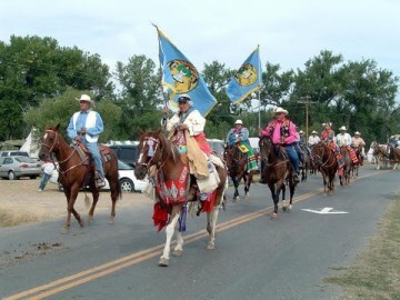 A procession of people on horseback going down a road.