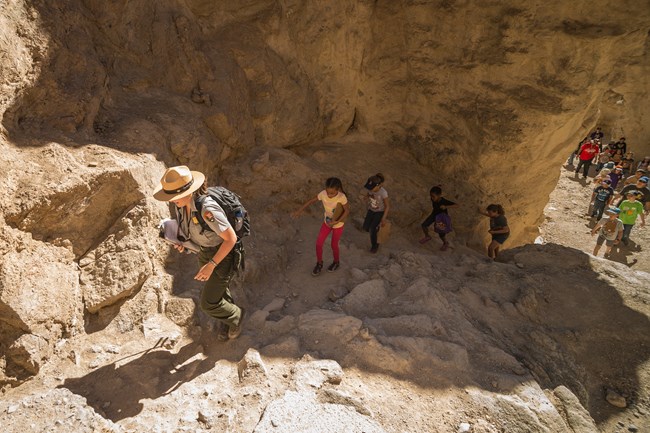 An education ranger leads children through a canyon.