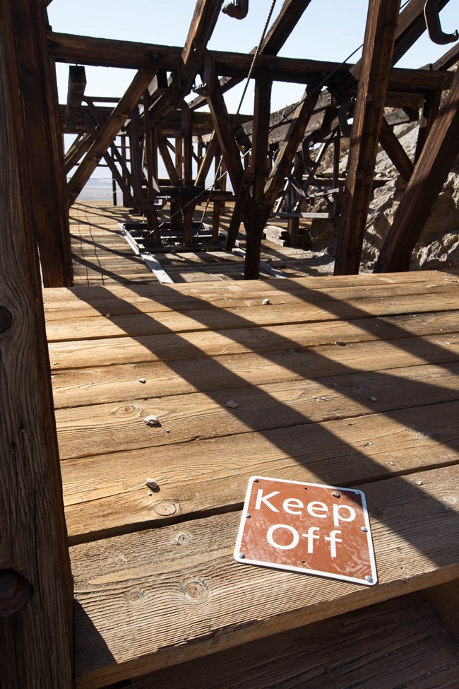 A keep off sign sits upon an old wooden structure in the desert.