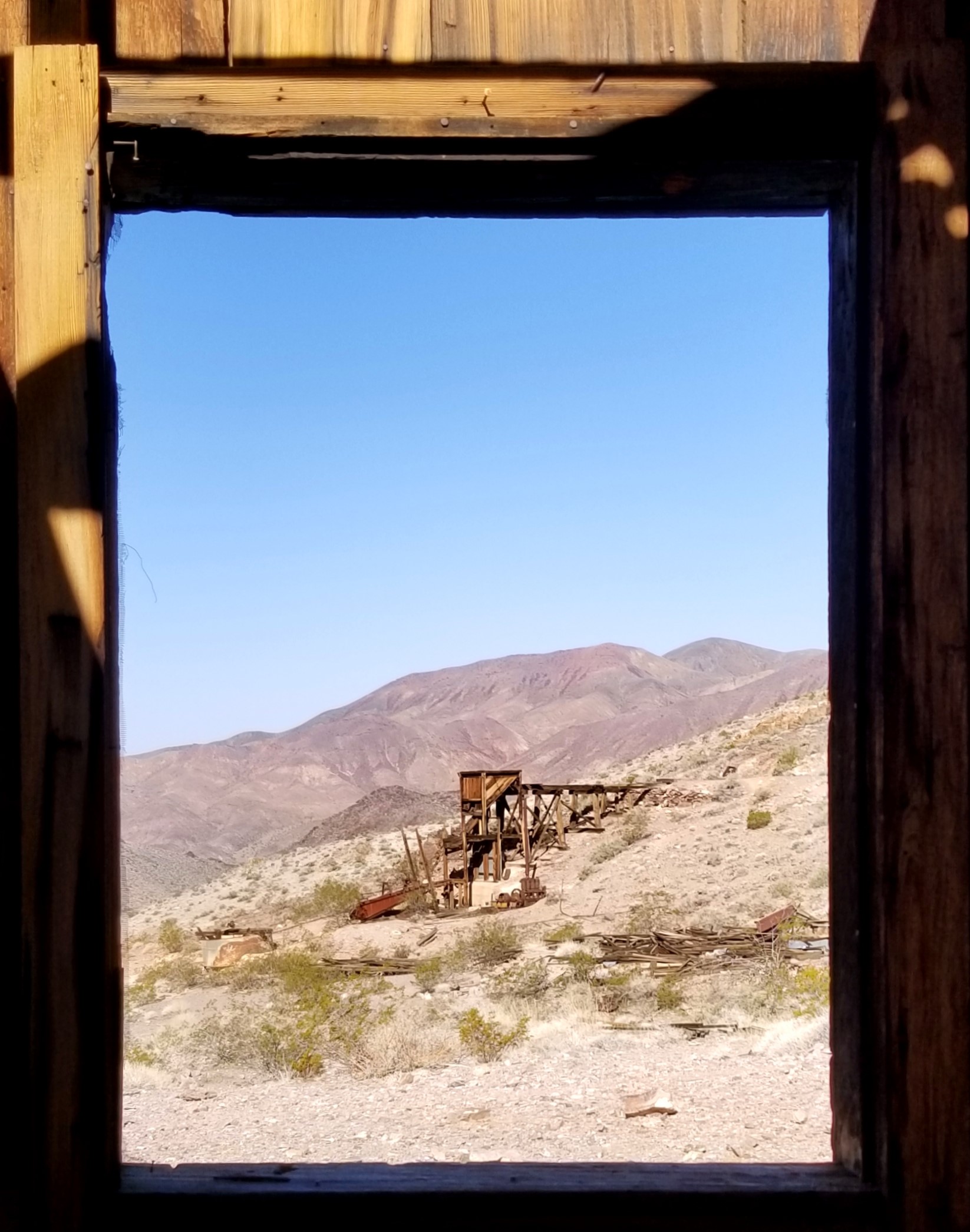 View of a distant wooden structure as seen framed by an old wooden window.