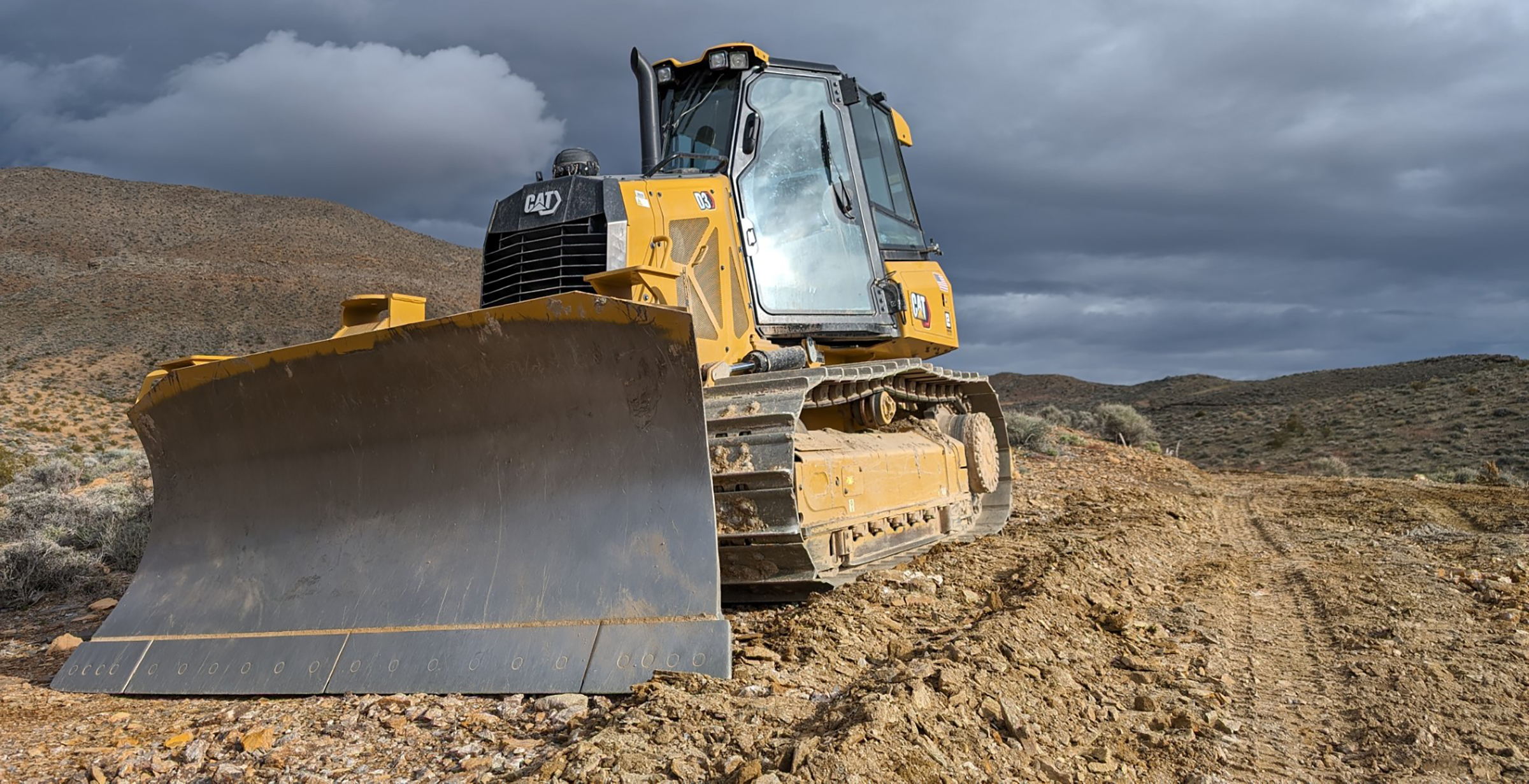 Yellow dozer on top of brown gravel and a stormy gray sky above.