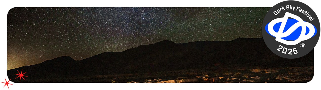 Starry night sky over the silhouettes of mountains.