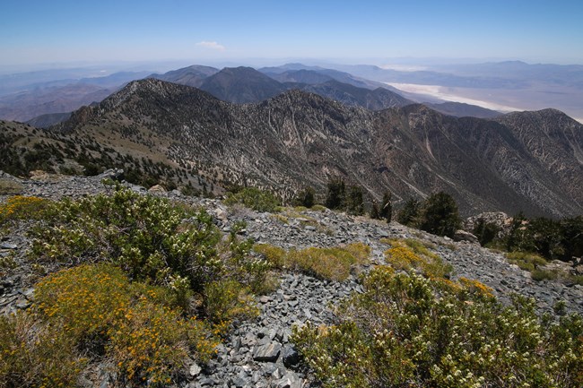 On top of desert mountain, looking out at the distant desert valley below.