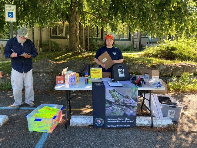 An intern stands behind a table with safety equipment on it.