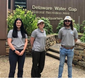 Three people standing next to each other in front of the park headquarters building.