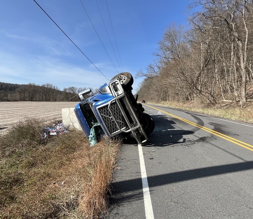A blue-cabbed tractor trailer flipped on its side along route 209.