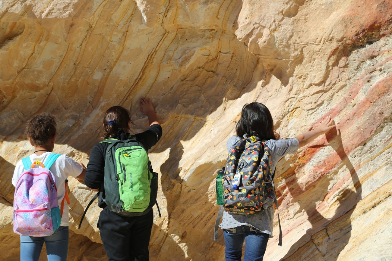 Students touch a rock while on a field trip.