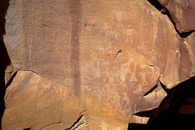 Faint human-like images pecked into a rock face