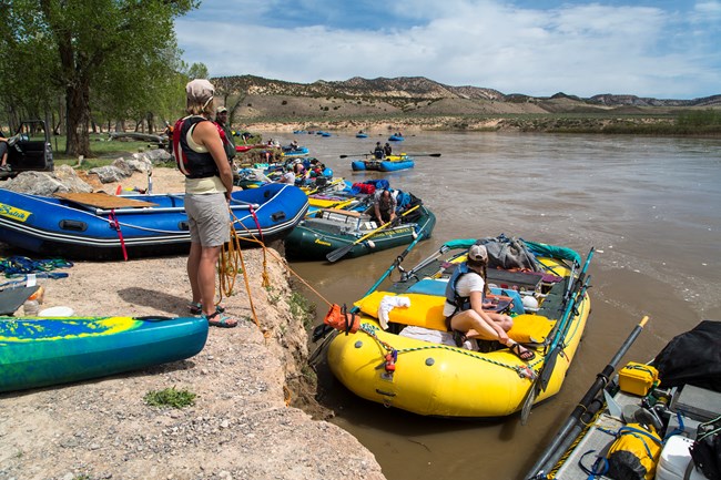 A rafting trip launching from Deerlodge Park. Numerous rafts and people are in the water.