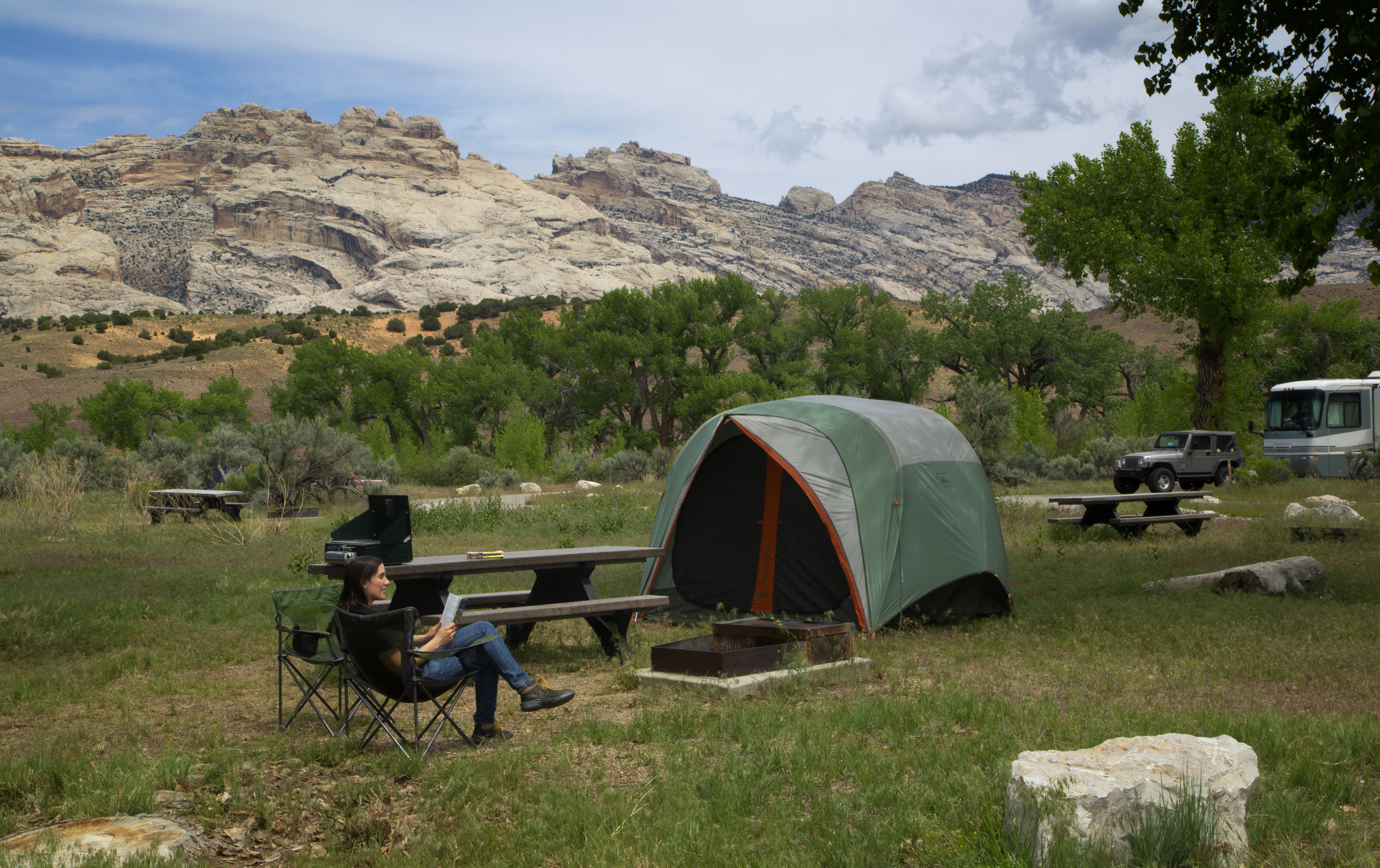 Woman sitting in a chair in front of a tent with a rock mountain in the background
