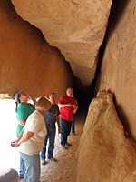 A group of visitors takes a look at the gash in the sandstone known as Whispering Cave.