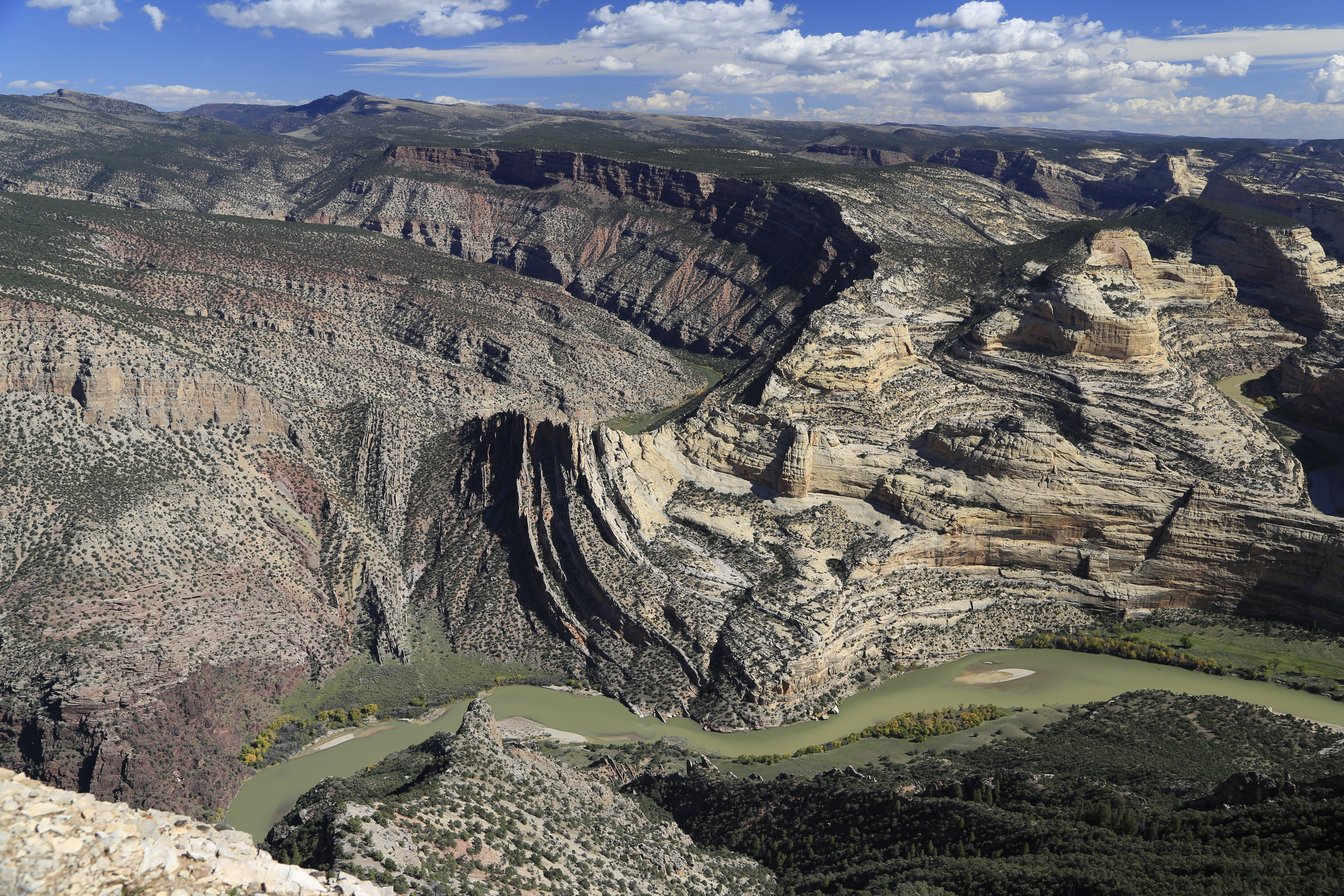 View of tan and multi-colored cliffs rising above a river