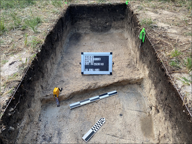 Image shows a building foundation revealed during an archeology excavation. There are several tools and flagging to mark the area.