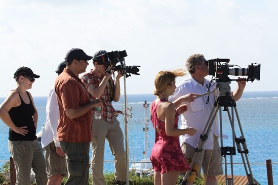 people standing and holding photography and filming equipment with blue ocean waters in the background