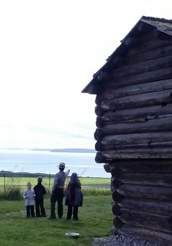 Ranger and kids stand by historic structure and look at the horizon