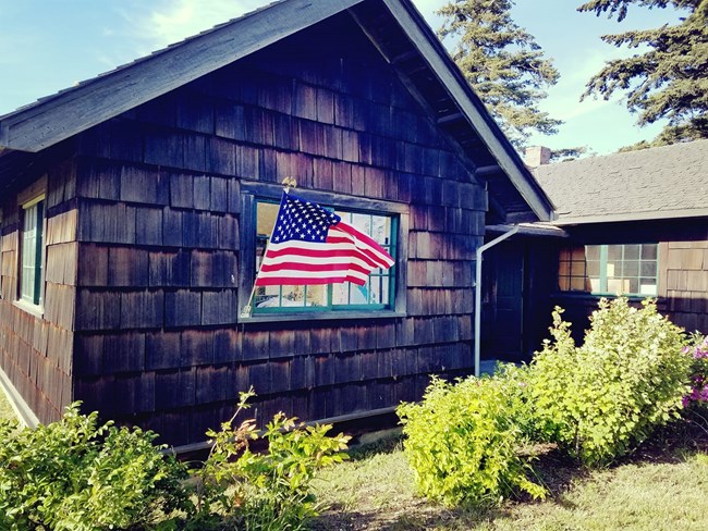 Wood shingled cottage with American flag flying.