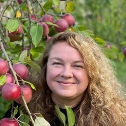 Smiling woman in front of apple tree