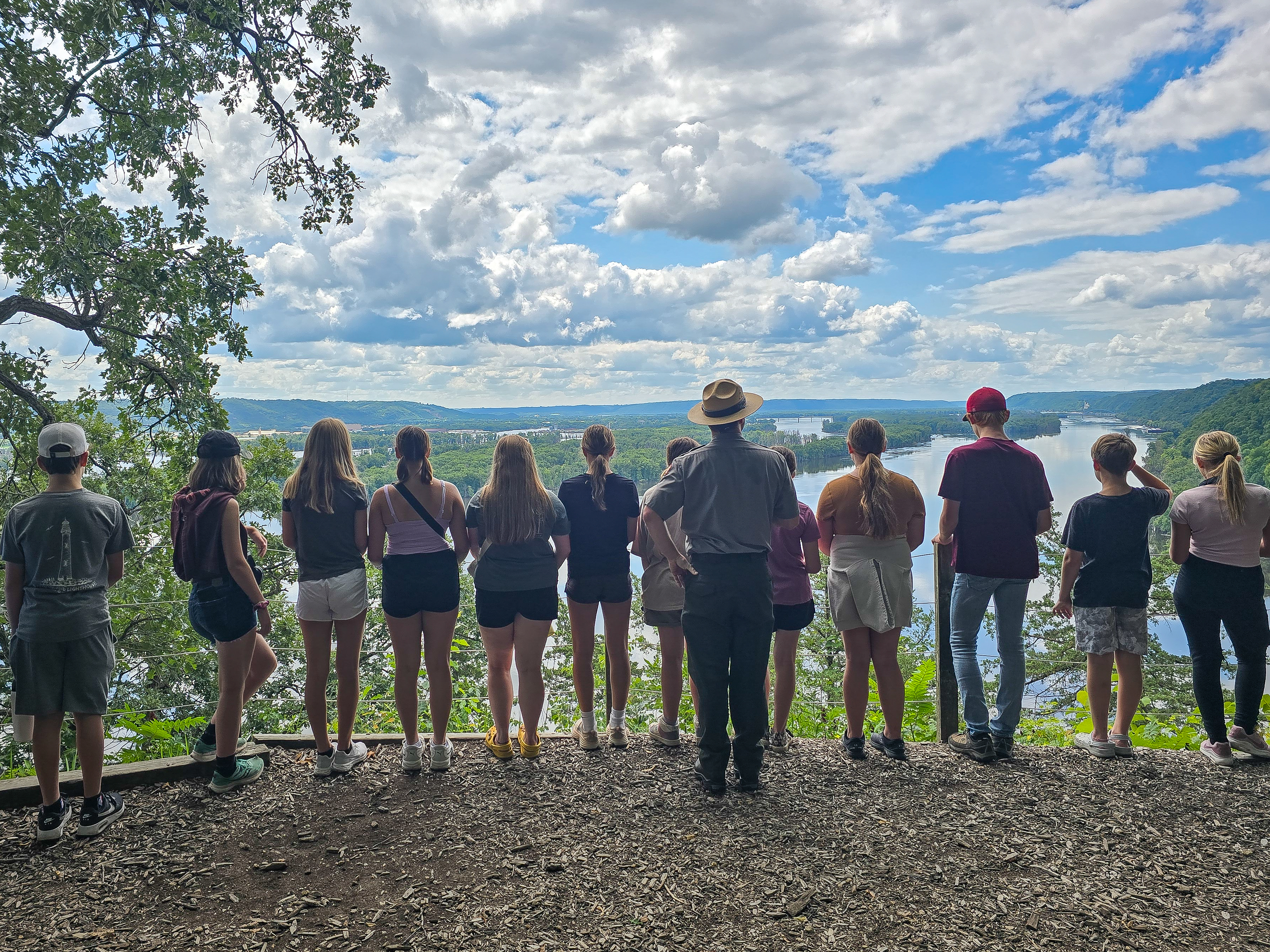 Image of the back of a park ranger and group of children overlooking the river.
