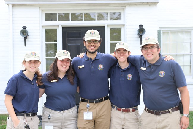 Five interns stand side by side in blue polo shirts