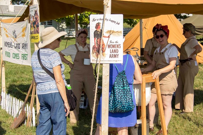 Visitors interact with living history volunteers at an outdoor tent at the Eisenhower National Historic Site