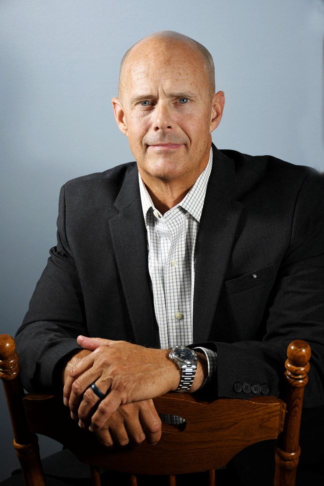 A color image of a man in a blue suit coat and blue shirt