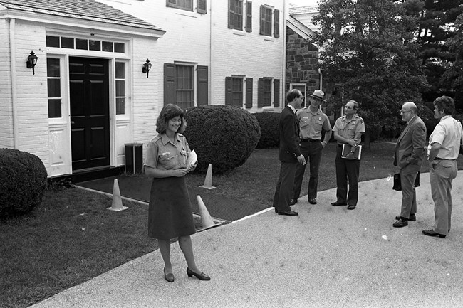 A black and white photo showing park staff and Eisenhower family members in front of the Eisenhower home
