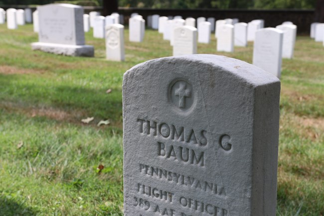 A color photograph of a white marble headstone with the name Thomas Baum