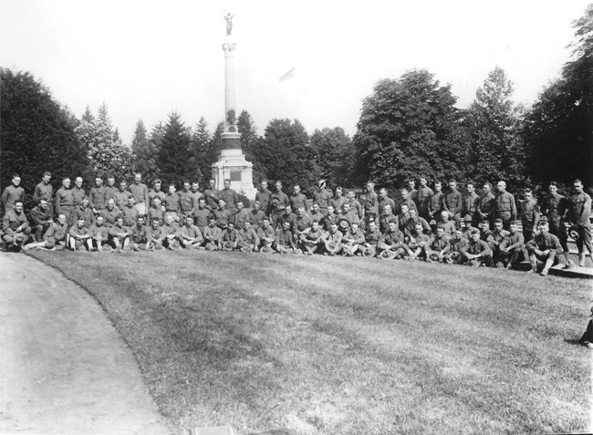 A group of soldiers stands in front of a tall monument