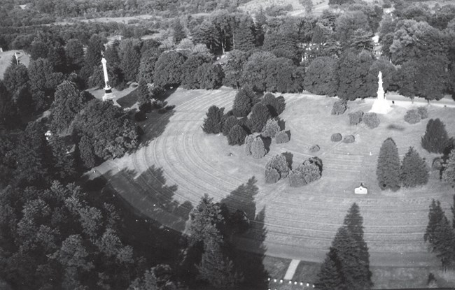 aerial view of gravestones in a cemetery with a large monument in the distance