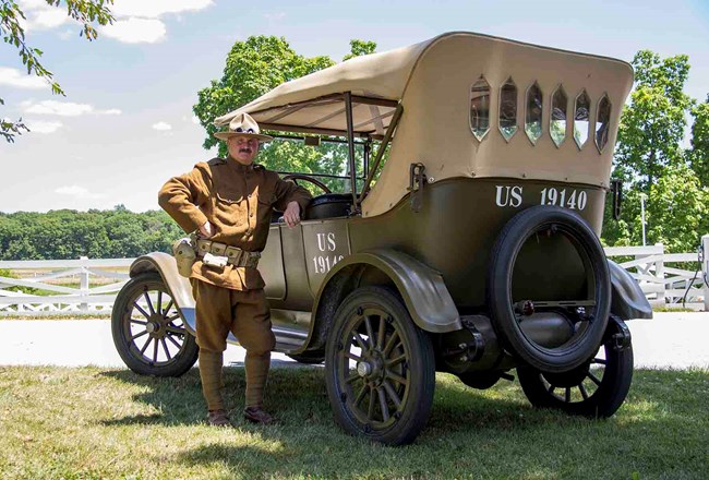 WWI solider standing next to car