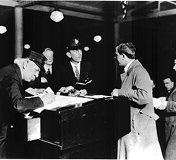 Three men stand around an inspector's desk