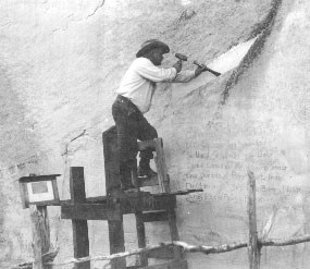 Image of the first superintendent chiseling a groove in the rock to reroute water flows around an old Spanish inscription