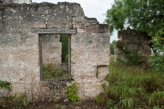 Ruins of rough hewn stone building with wood-framed window
