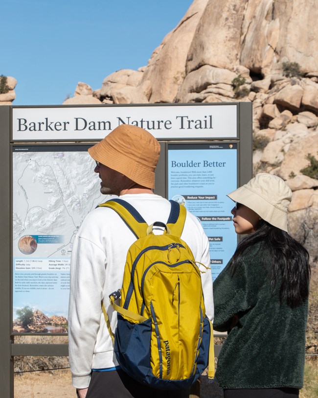 Dos visitantes del parque frente al tablón de información.