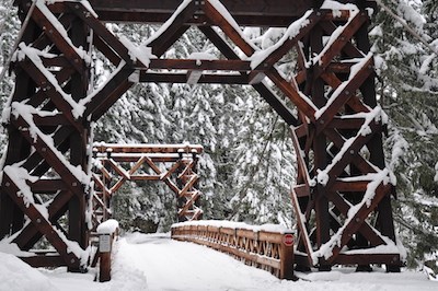Puente colgante de madera cubierto de nieve.