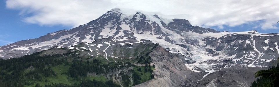 Un gran glaciar circunda la ladera de una elevada montaña descendiendo hacia un valle profundo.