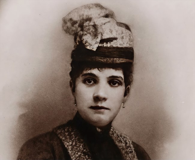 A woman who is elegantly dressed, poses for the camera.